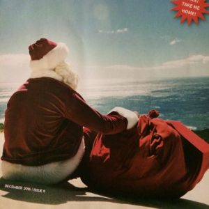 Santa sitting on the beach, facing the water